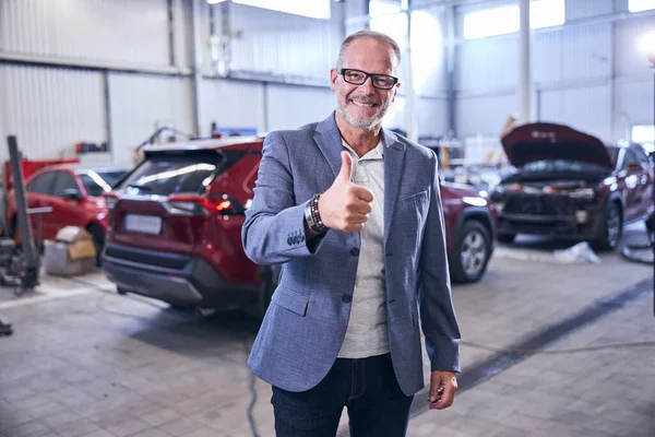 Fröhlicher Mann zeigt an Kfz-Werkstatt Geste der Zustimmung — Stockfoto