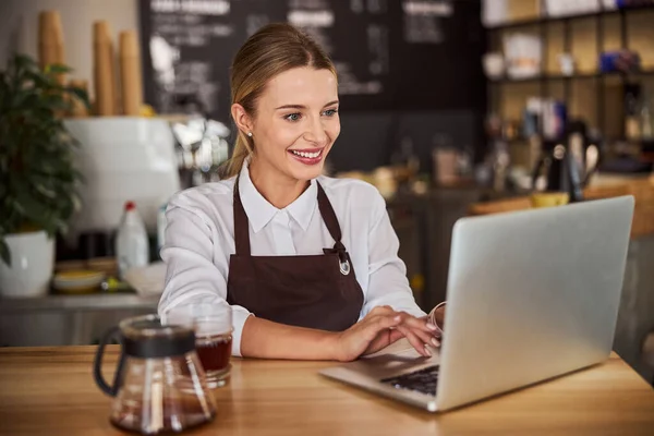 Verkoopster werkt op de laptop in de coffeeshop — Stockfoto