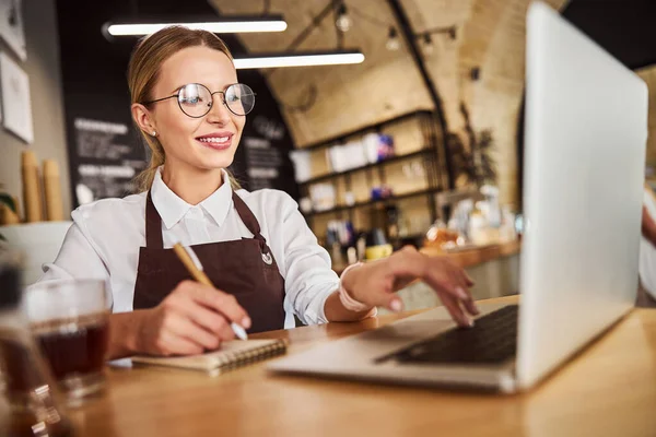 Feliz dama sonriente en uniforme usando el ordenador portátil en el trabajo —  Fotos de Stock