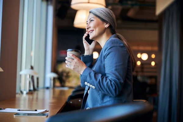 Neşeli iş kadını cep telefonuyla konuşuyor ve kahve içiyor. — Stok fotoğraf