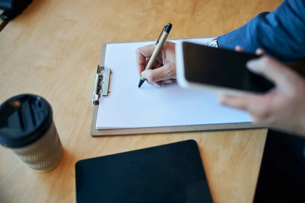 Mani femminili usando il cellulare e scrivendo negli appunti — Foto Stock