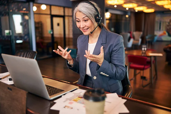 Glada kvinna som har online-samtal med kollega på jobbet — Stockfoto