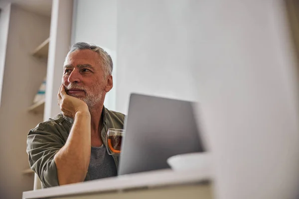 Pensive-looking aging man sitting in front of computer screen — Stock Photo, Image