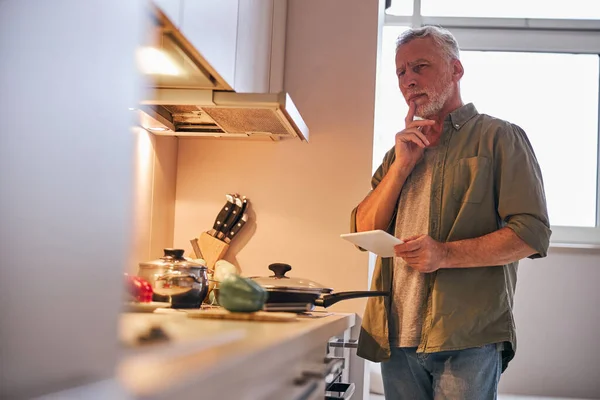 Ηλικιωμένος άντρας στο σπίτι σκέφτεται να παραγγείλει φαγητό online παράδοση — Φωτογραφία Αρχείου