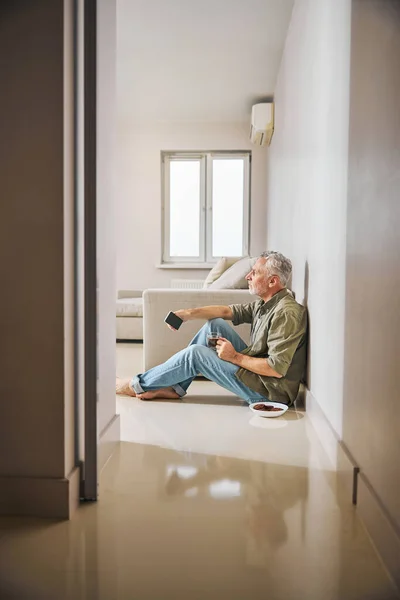 자기 아파트 바닥에서 차를 마시고 있는 노인 — 스톡 사진