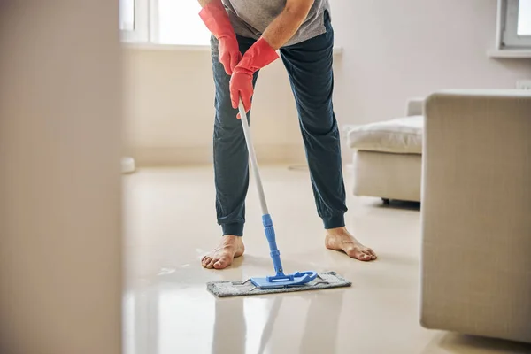 Plichtsgetrouwe man die zijn appartement schoonmaakt met een dweil — Stockfoto