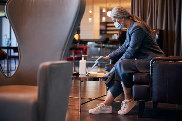 Mulher elegante em máscara médica usando laptop no centro de negócios — Fotografia de Stock