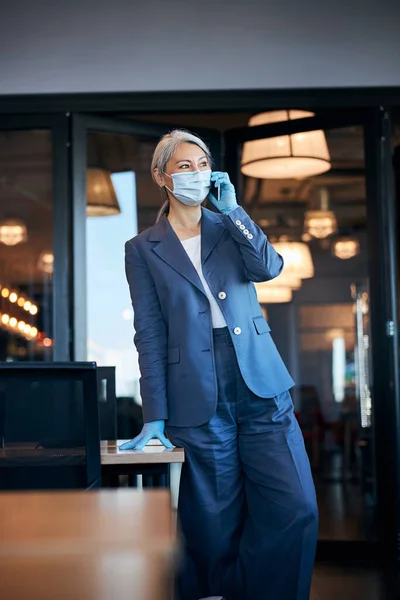 Elegante vrouw met medisch masker in gesprek op mobiele telefoon — Stockfoto