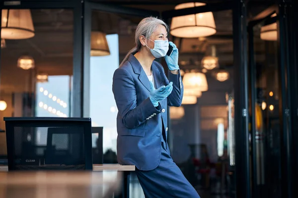 Бізнес-леді в захисній масці для обличчя розмовляють на мобільному телефоні — стокове фото