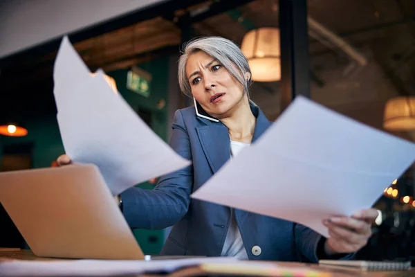 Charmante Geschäftsfrau studiert Dokumente und telefoniert — Stockfoto