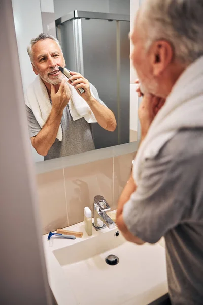 Aging gentleman doing some hair grooming in his bathroom — Stock Photo, Image