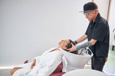 Berber saç işlemleri için saçı lavaboda tutuyor.