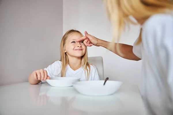 Carino perdere in camicia bianca guardando sua madre mentre seduto a tavola la mattina — Foto Stock