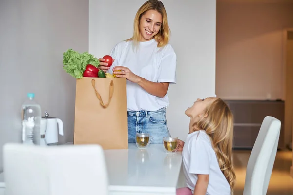 Felice madre allegra con verdure in sacchetti di carta a casa — Foto Stock
