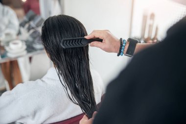 Adam saç fırçasıyla yarı ıslak saçlarını tarıyor.