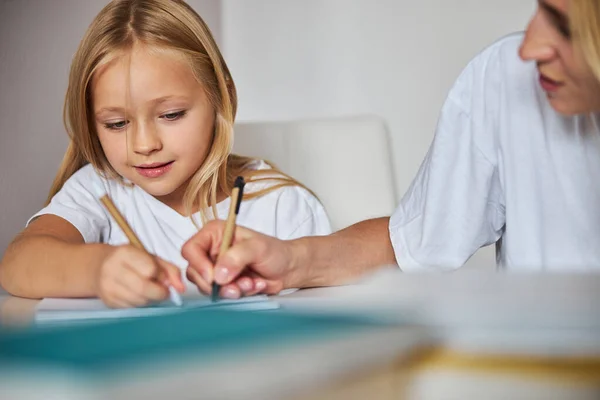 Gelukkig glimlachend vrouwelijk kind tijd doorbrengen met haar moeder bij de oefeningen boek — Stockfoto