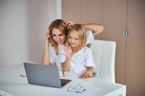 Funny beautiful mother with little daughter talking online with family from home — Stock Photo, Image