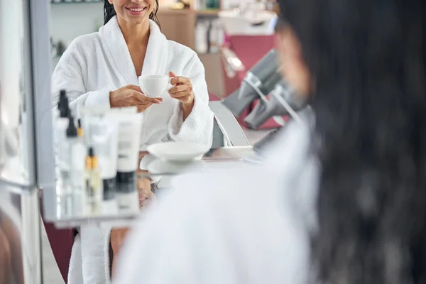 Mujer disfrutando de la bebida mientras se sienta en el sillón — Foto de Stock