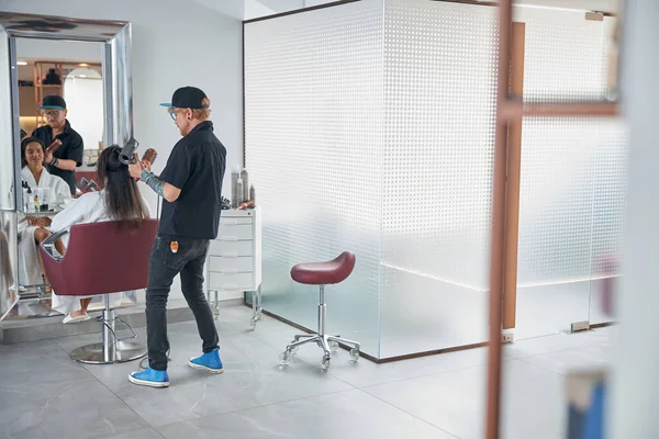 Estilista usando ferramentas e fazendo o cabelo olhar bem — Fotografia de Stock