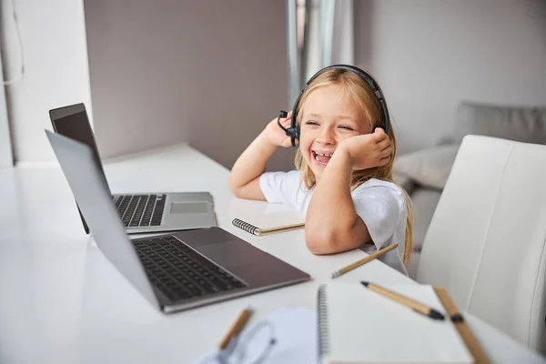 Happy smiling little miss in white shirt having fun while looking something on screen her two laptops in room indoor — Stock Photo, Image