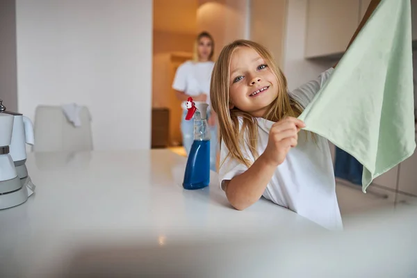 Glückliche fröhliche Tochter hilft ihrer Mutter am Wochenende beim Putzen der Wohnung — Stockfoto