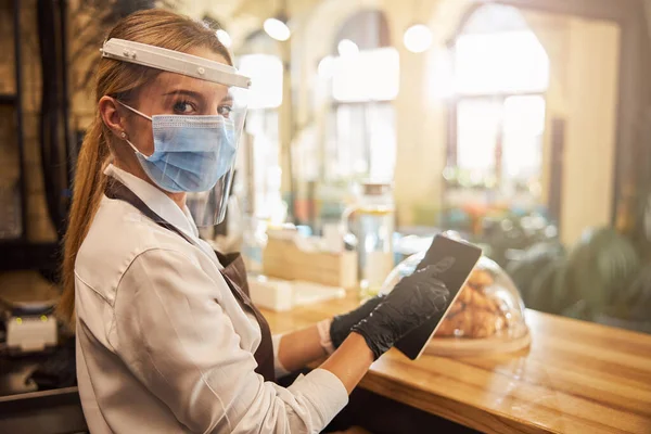 Trabajador de café usando un dispositivo moderno mientras hace la factura — Foto de Stock