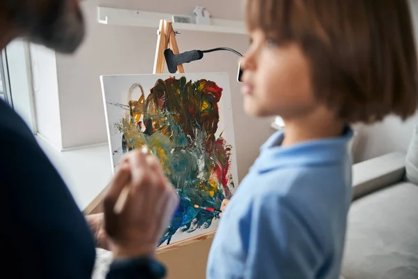 Canvas with abstract painting being made by dad and son