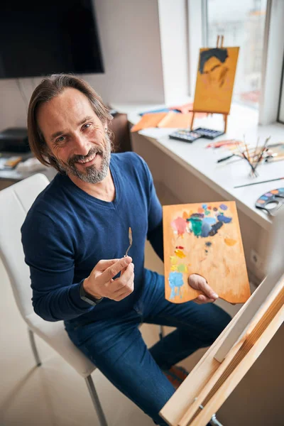 Uśmiechnięty artysta z paletą kolorów pracujących nad malowaniem — Zdjęcie stockowe