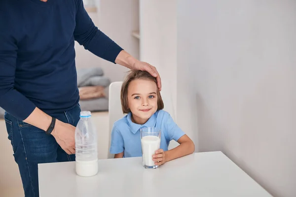 Carino ragazzo con un bicchiere di latte al tavolo della cucina — Foto Stock