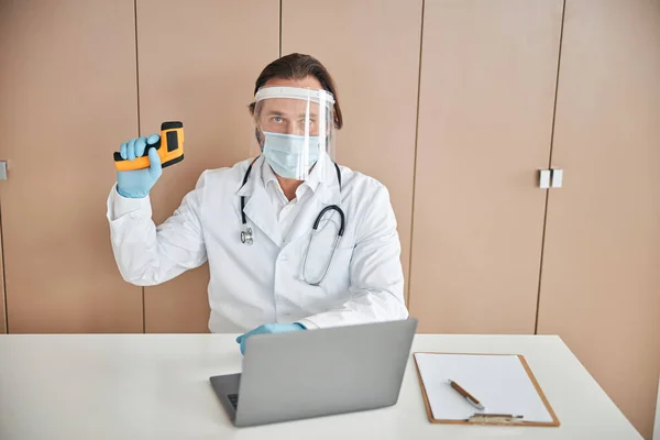 Professionele arts met een thermometer in de hand poseren in het kantoor — Stockfoto