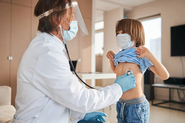 Professional doctor examining a kid with a stethoscope — Stock Photo, Image