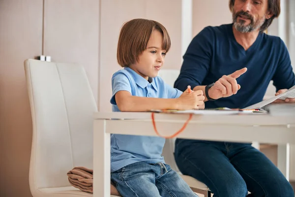 Inteligente niño hace tareas y el padre le ayuda —  Fotos de Stock