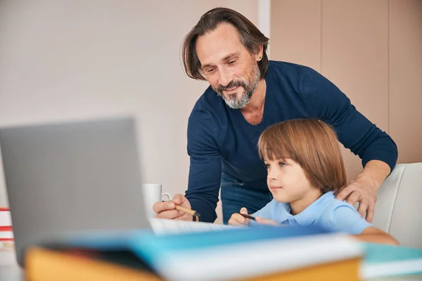 Hombre alegre animando a su hijo a hacer la tarea —  Fotos de Stock