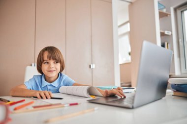 Gülümseyen çocuk çevrimiçi ders için programı açıyor.