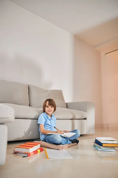 Leuke jongen die thuis studeert en er vrolijk uitziet — Stockfoto