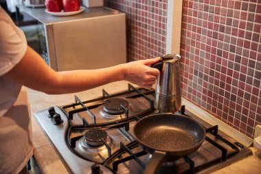 Su ısıtıcısını ocağa koyan kişi