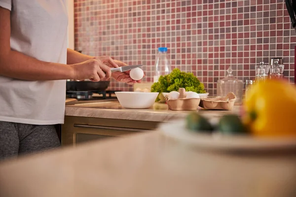 Volwassen vrouw die een ei breekt boven een kom — Stockfoto