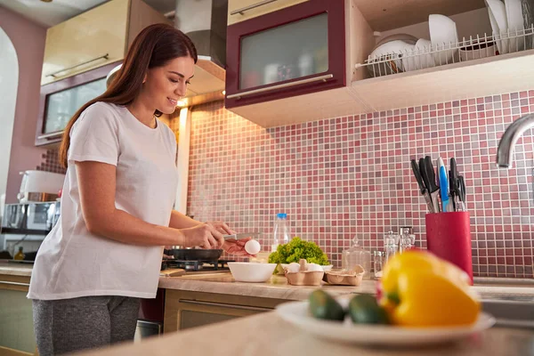 Vrouw die een mes vasthoudt en een ei breekt — Stockfoto