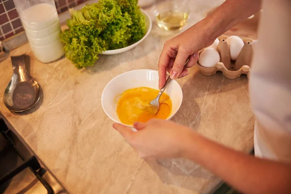 Доросла жінка збиває яйця з ложкою — стокове фото