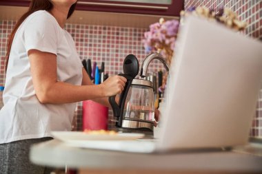 Ev hanımı çaydanlığa su çekiyor.