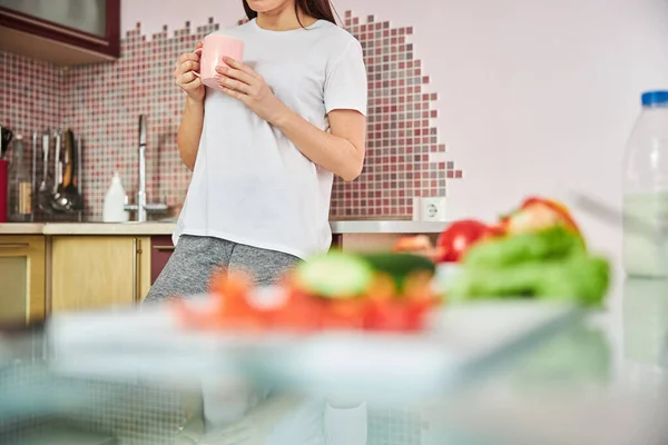 Persoon met een theebeker leunend op een kooktafel — Stockfoto