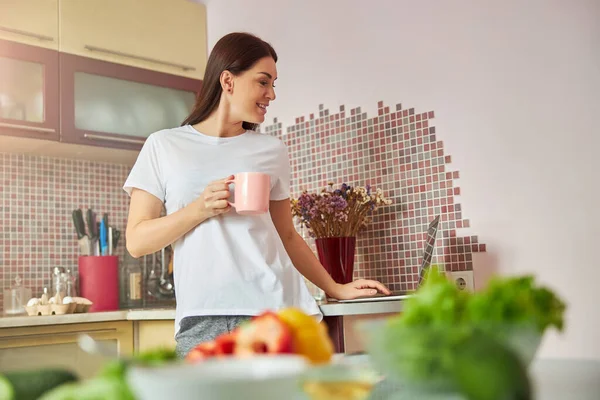 Zelfverzekerde huisvrouw surfen op internet met een laptop — Stockfoto