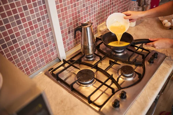 Mulher adulta derramando omelete para uma frigideira — Fotografia de Stock