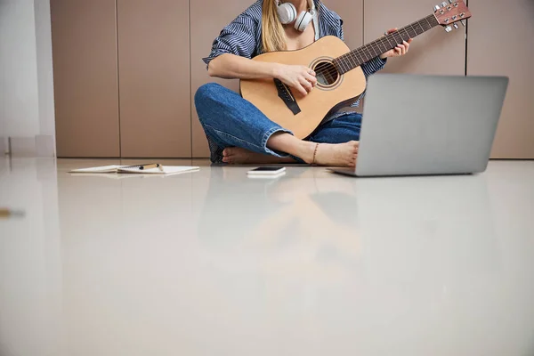 Músico feminino tocando guitarra e usando laptop em casa — Fotografia de Stock