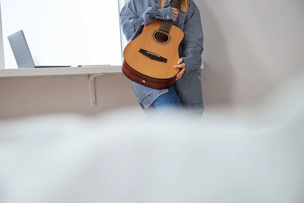 Músico femenino con guitarra de pie junto a la ventana en casa — Foto de Stock