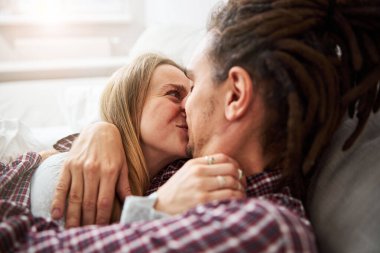 Güzel bir çift yatakta sarılıp öpüşüyor.