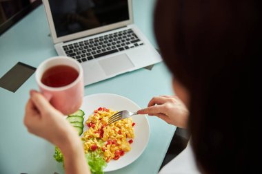 Çatallı bir kadın kahvaltısını yiyor.