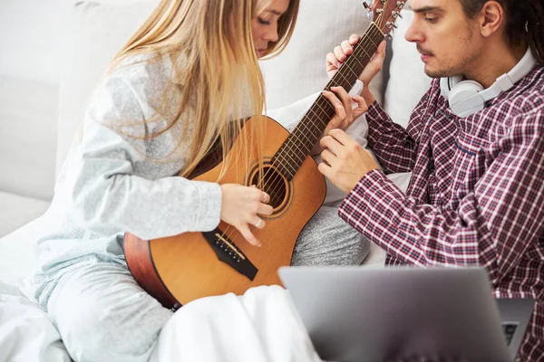 Amoroso jovem ensinando sua namorada a tocar guitarra em casa — Fotografia de Stock
