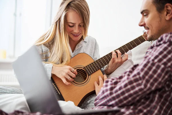Jovem alegre tocando guitarra e passando tempo com o namorado — Fotografia de Stock
