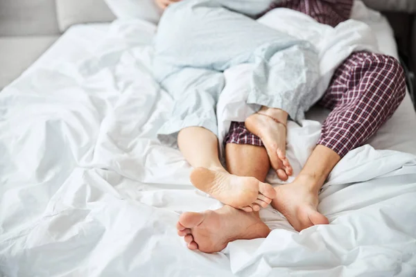 Gelukkig paar in liefde rusten in bed met verweven benen — Stockfoto